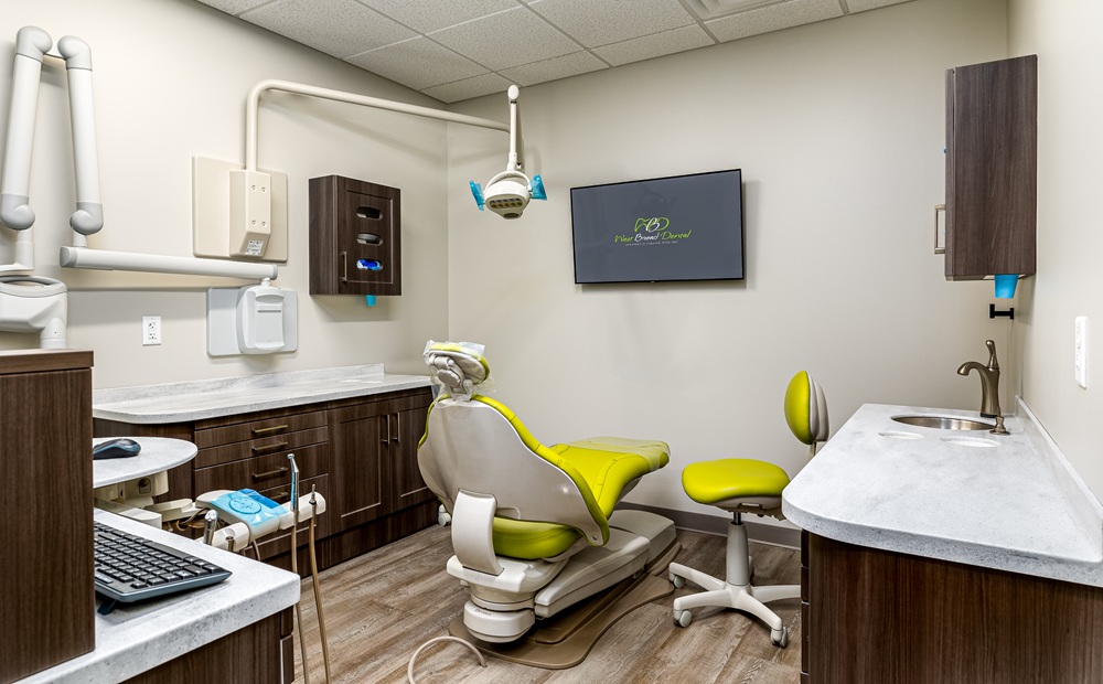Fully equipped dental operatory at West Broad Dental featuring a modern green patient chair and digital monitors.