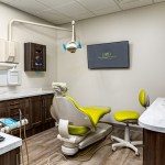 Fully equipped dental operatory at West Broad Dental featuring a modern green patient chair and digital monitors.