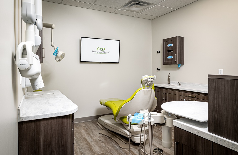 Clean clinical exam room at West Broad Dental with an intraoral X-ray unit and dental care equipment.
